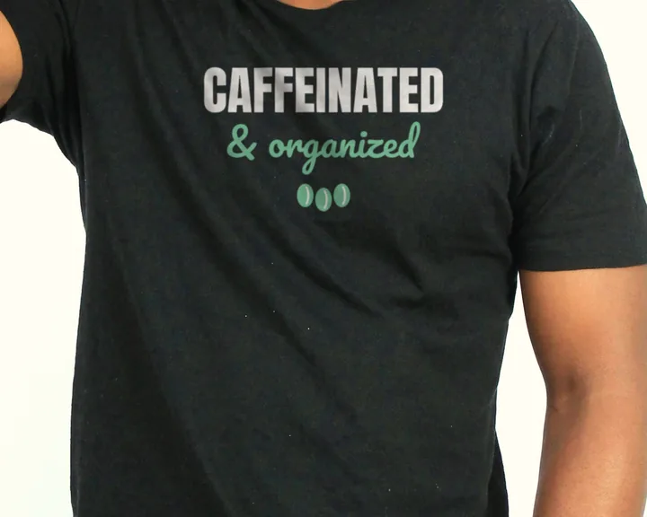 Man wearing a black "Caffeinated and Organized" tee in a bright studio (light-ink print for dark shirts)