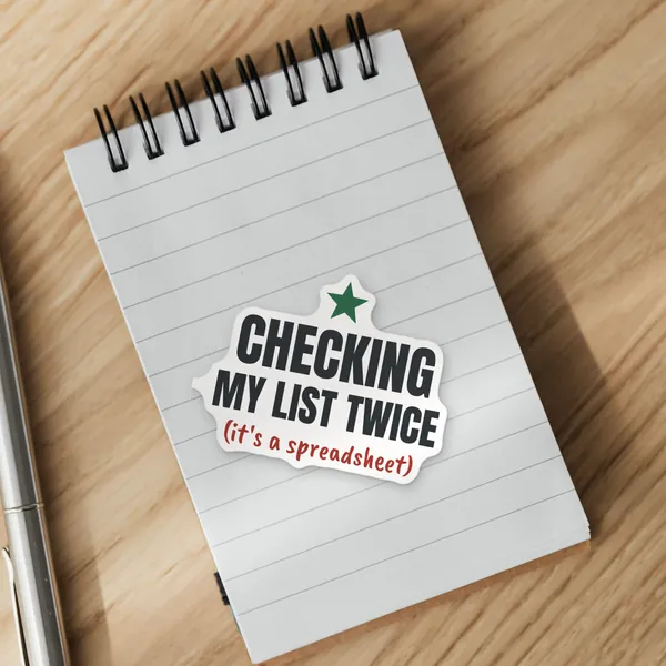 Die-cut "Checking My List Twice (It's a Spreadsheet)" vinyl sticker on a spiral notepad
