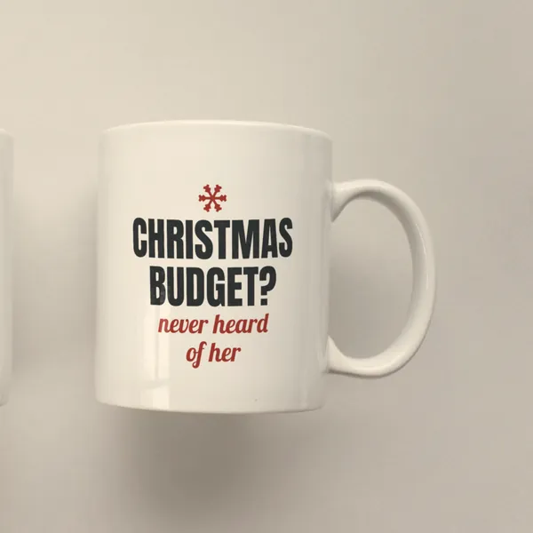 White 11 oz ceramic mug printed with "Christmas Budget? Never Heard of Her", side view