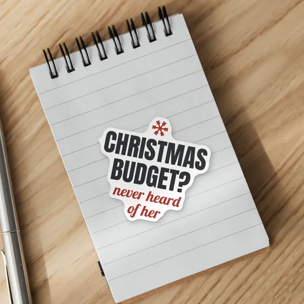 Die-cut "Christmas Budget? Never Heard of Her" vinyl sticker on a spiral notepad