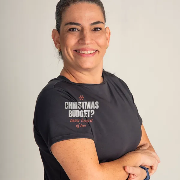 Woman wearing a black "Christmas Budget? Never Heard of Her" tee in a bright studio (light-ink print for dark shirts)