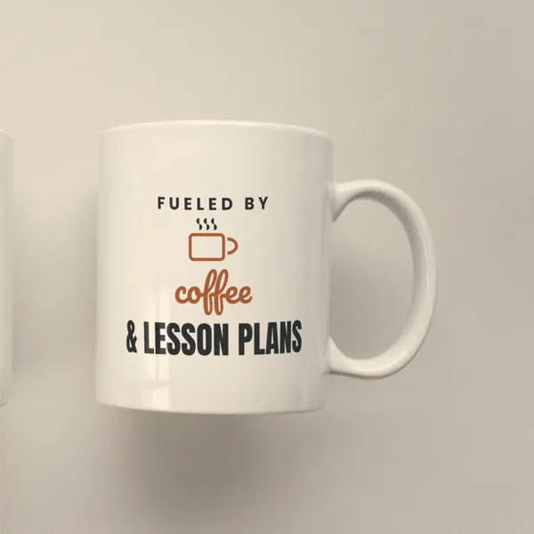White 11 oz ceramic mug printed with "Fueled by Coffee and Lesson Plans", side view
