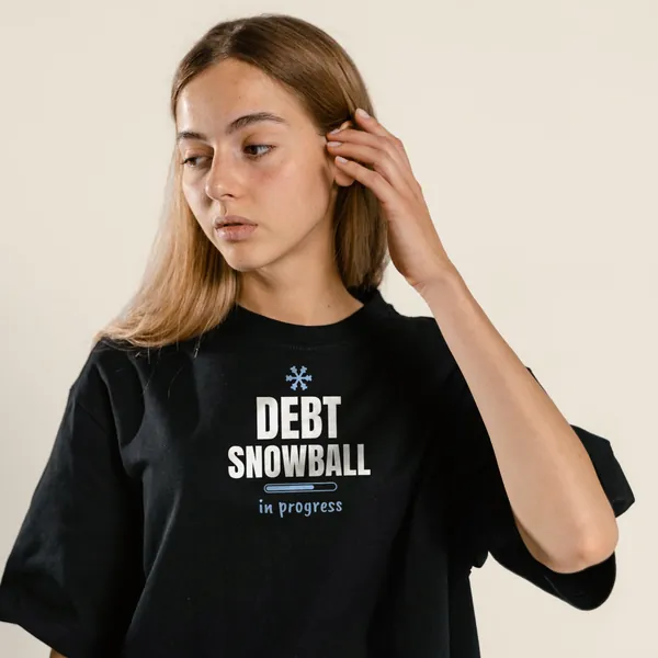Model wearing a black "Debt Snowball in Progress" tee with the light-ink version of the design