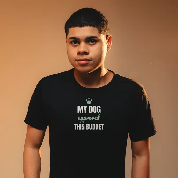 Man wearing a black "My Dog Approved This Budget" tee against a warm backdrop (light-ink print for dark shirts)