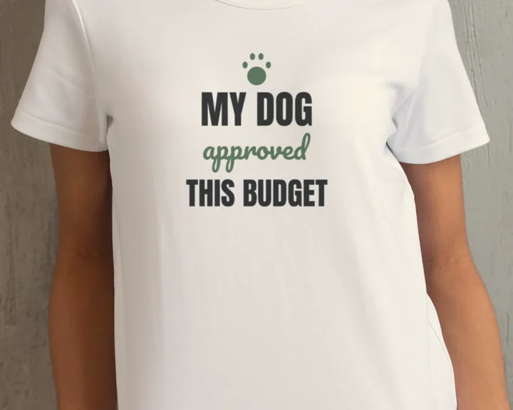 Woman wearing a white "My Dog Approved This Budget" tee by a concrete wall