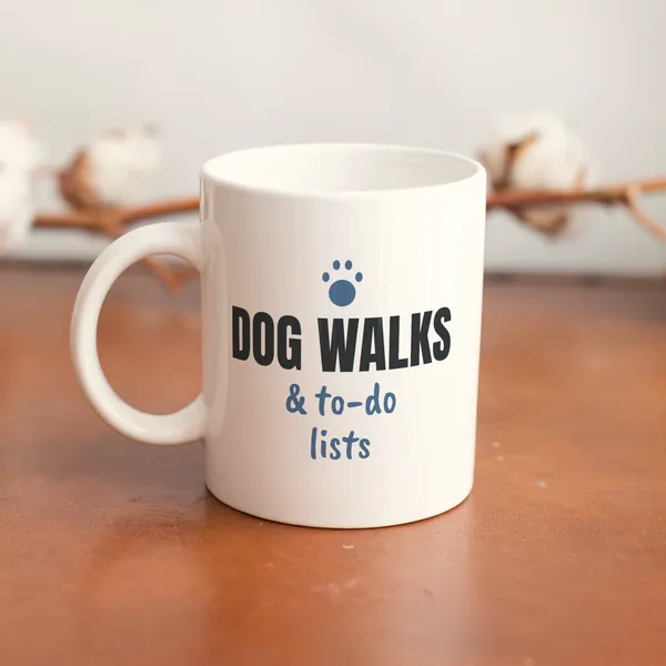 White 11 oz ceramic mug printed with "Dog Walks and To-Do Lists" on a wooden table