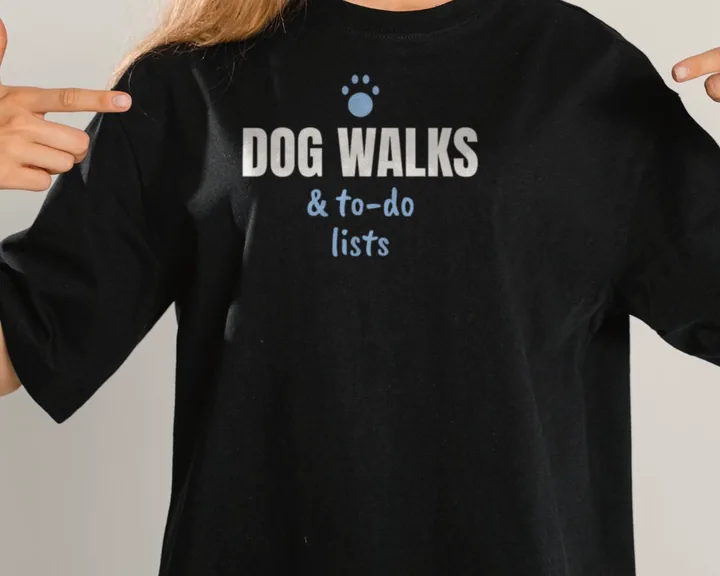 Woman wearing a black "Dog Walks and To-Do Lists" tee in a studio (light-ink print for dark shirts)