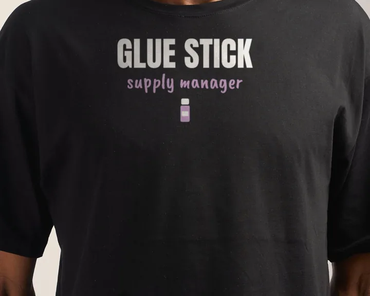 Man wearing a black "Glue Stick Supply Manager" tee in a studio (light-ink print for dark shirts)