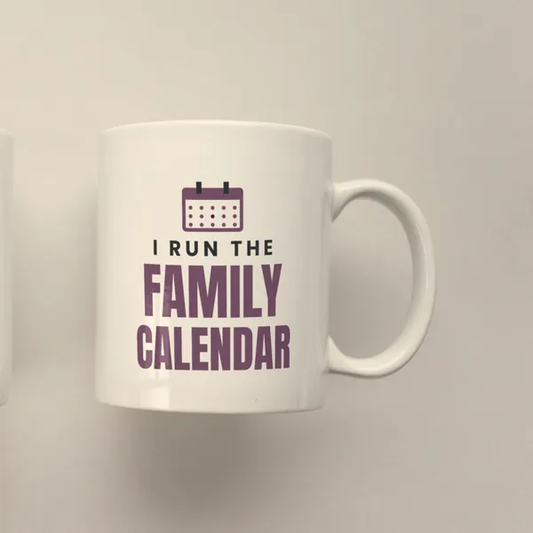 White 11 oz ceramic mug printed with "I Run the Family Calendar", side view