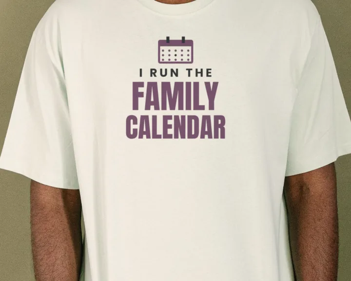 Man wearing a white "I Run the Family Calendar" tee in a warm studio