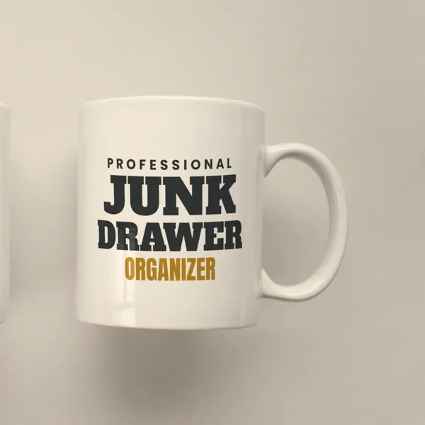 White 11 oz ceramic mug printed with "Professional Junk Drawer Organizer", side view