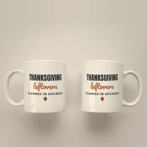 Two white 11 oz ceramic mugs printed with "Thanksgiving Leftovers Planned in Advance", handles left and right