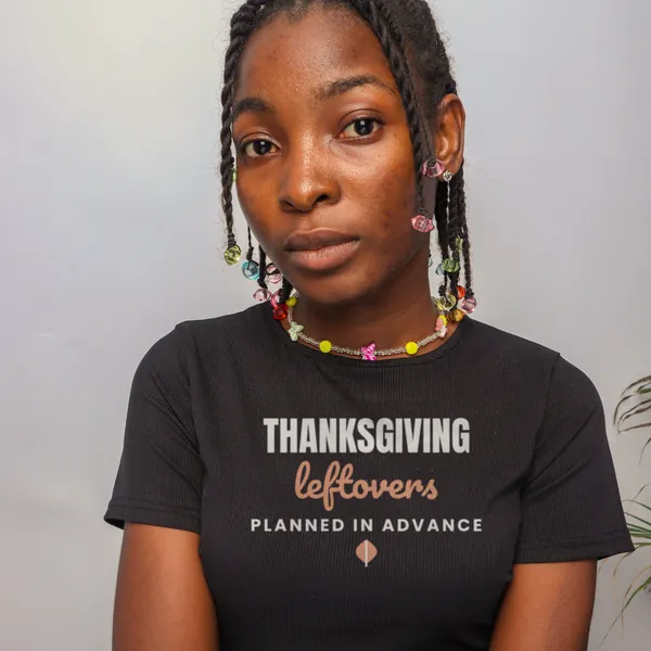 Woman wearing a black "Thanksgiving Leftovers Planned in Advance" tee in a studio (light-ink print for dark shirts)