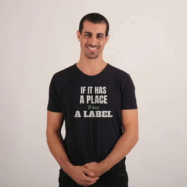 Man wearing a black "If It Has a Place, It Has a Label" tee in a studio (light-ink print for dark shirts)