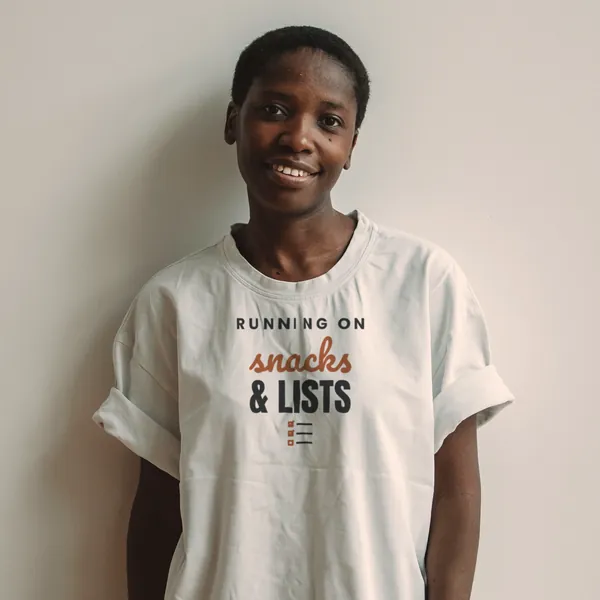 Woman wearing a white "Running on Snacks and Lists" tee in a bright studio