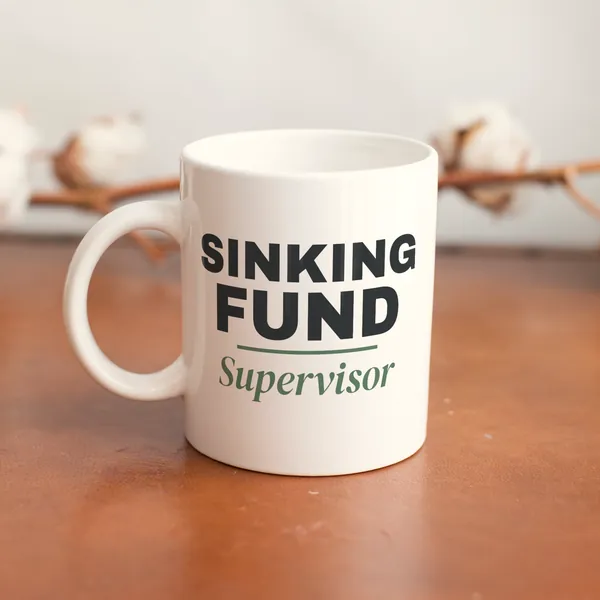 White 11 oz ceramic mug printed with "Sinking Fund Supervisor" on a wooden table