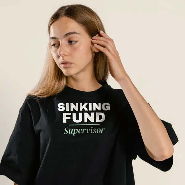 Model wearing a black "Sinking Fund Supervisor" tee with the light-ink version of the design