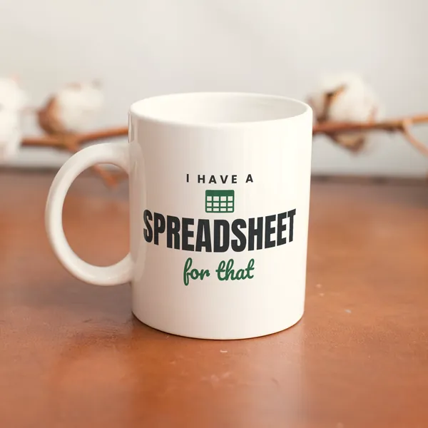 White 11 oz ceramic mug printed with "I Have a Spreadsheet for That" on a wooden table