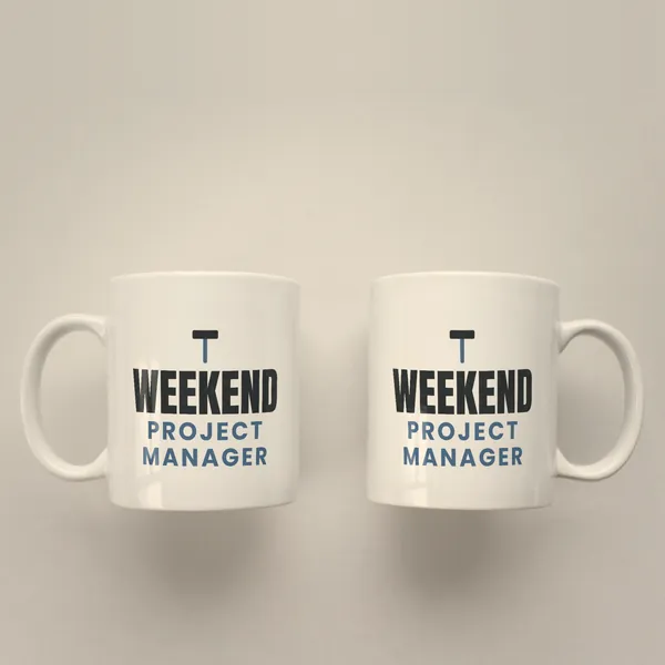 Two white 11 oz ceramic mugs printed with "Weekend Project Manager", handles left and right