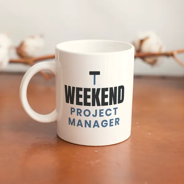 White 11 oz ceramic mug printed with "Weekend Project Manager" on a wooden table
